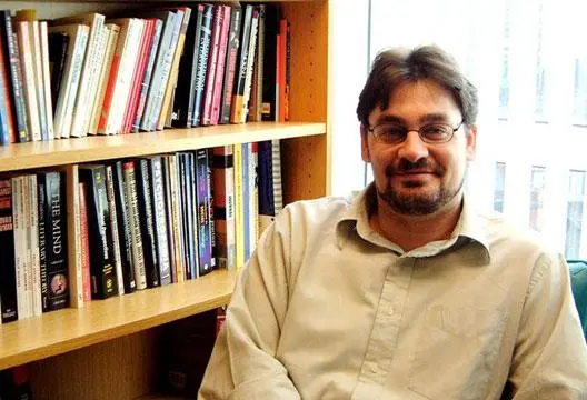 Mark Griffiths, author and professor, sitting beside a bookshelf in an academic office
